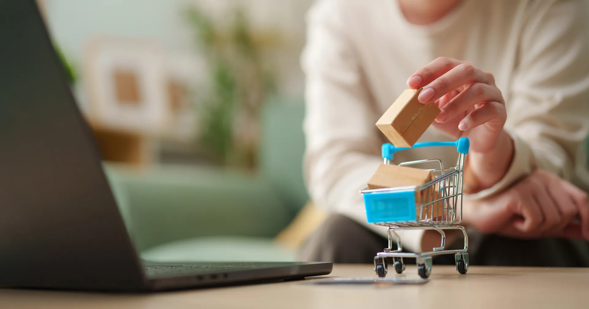 Vrouw voegt miniatuurverpakking toe aan winkelwagen naast de laptop